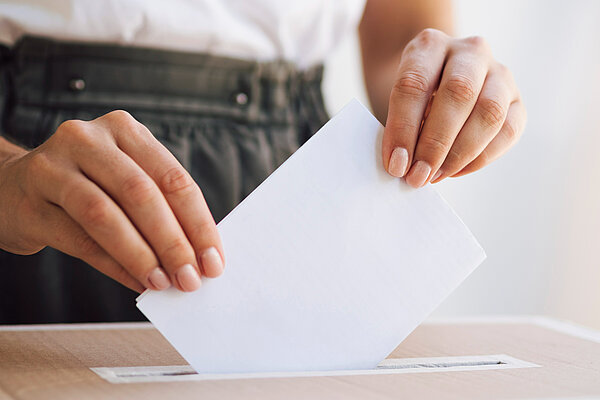 A person putting a ballot paper into a ballot box